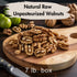 A 20 lb. box of natural raw unpasteurized walnuts presented on a wooden cutting board with a knife on the side, apples in the background, and a text overlay defining the product.